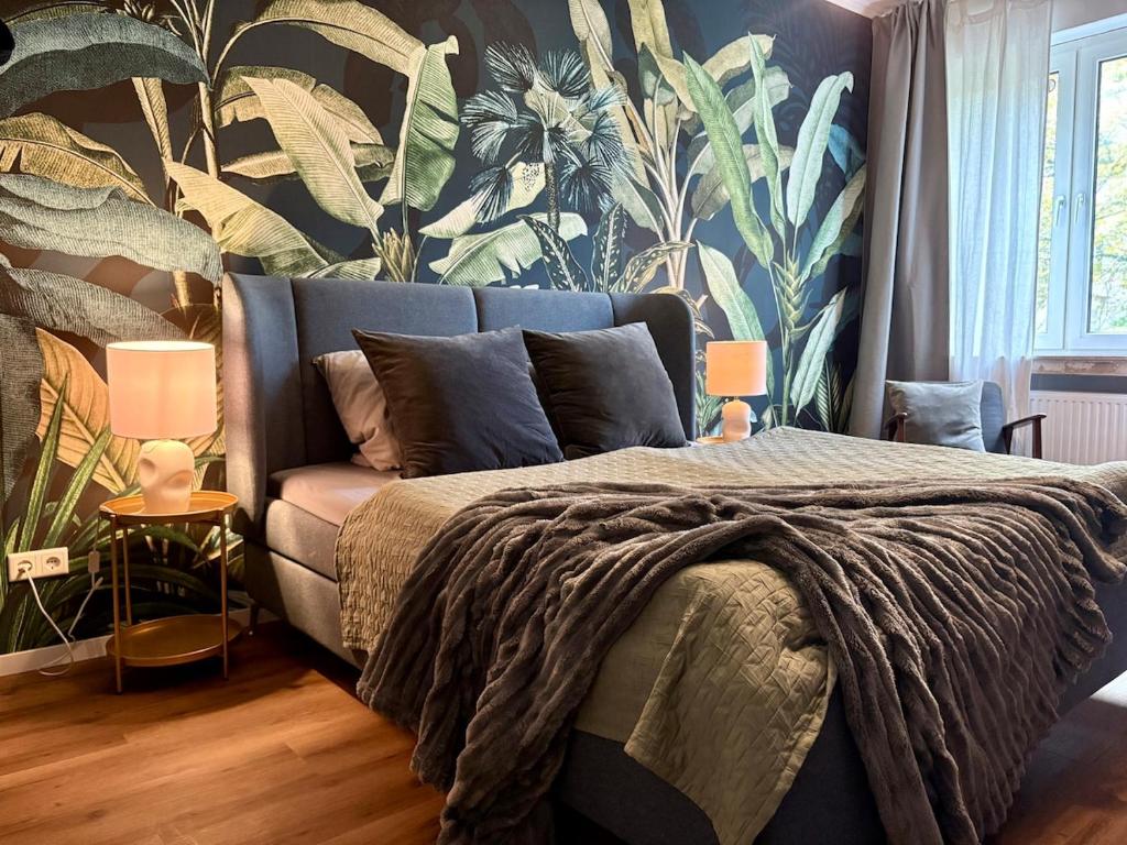 a bedroom with a blue bed with a tropical wallpaper at My happy place - Apartment mit Sauna & Whirlpool in Essen