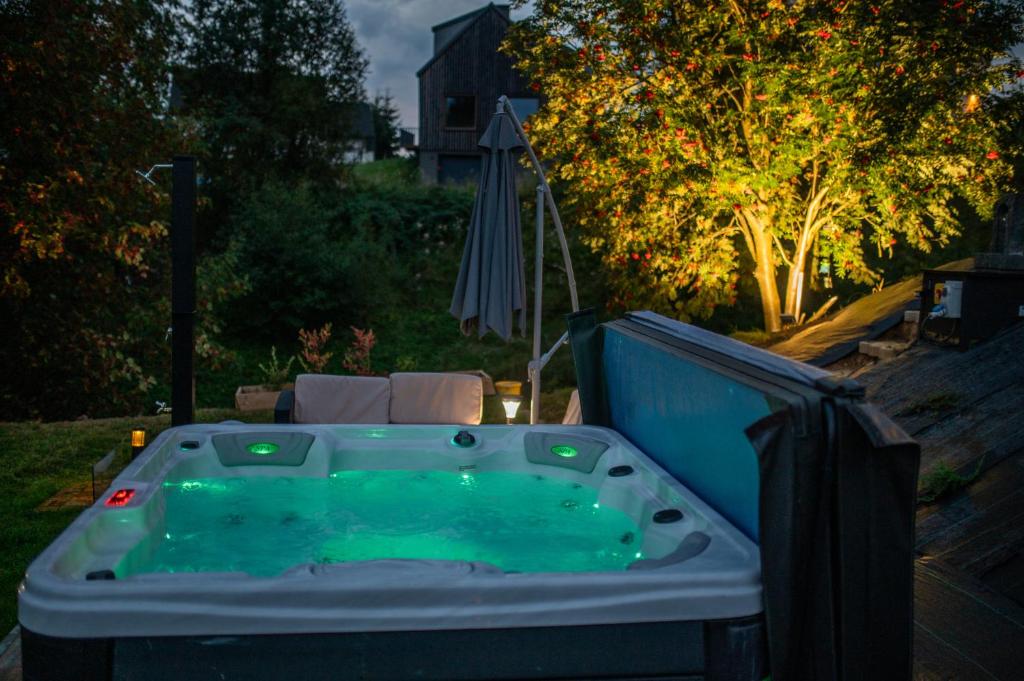 a jacuzzi tub in a yard with an umbrella at StyLove Domki 1 in Kluszkowce