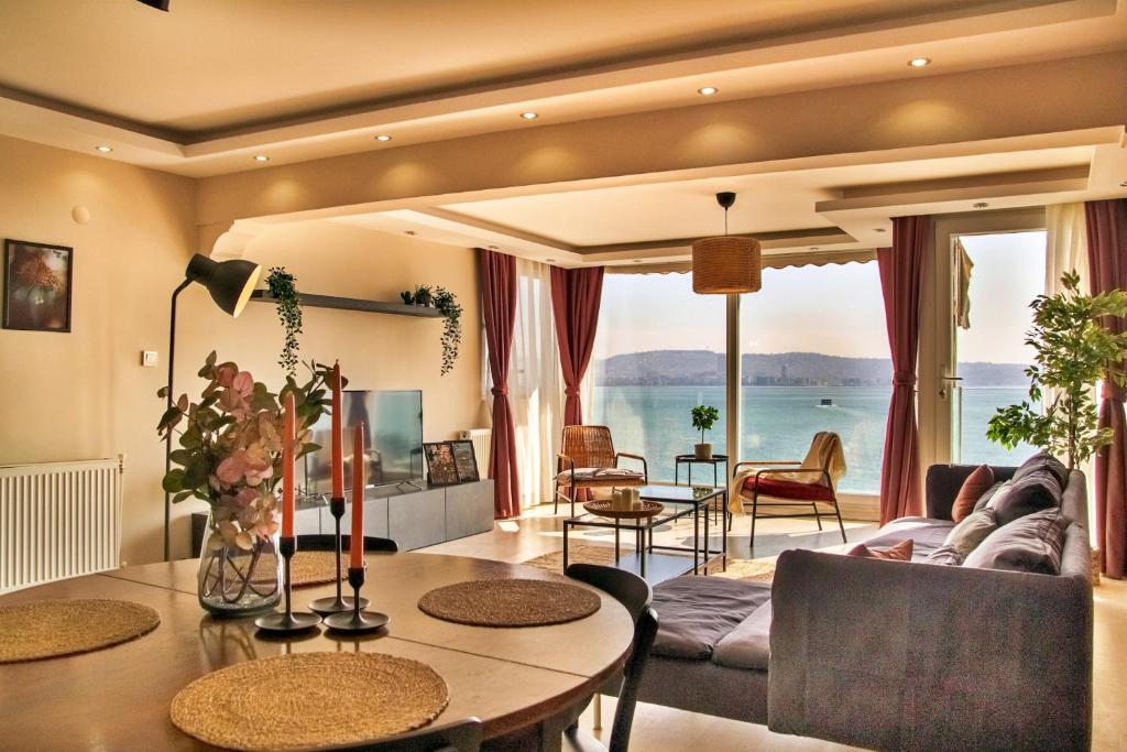 a living room with a table and a view of the ocean at Sea View 3BR Flat – Steps from Coast Road in Izmir