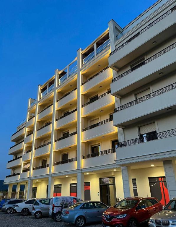 a large building with cars parked in front of it at Apartman Kristal, Vrnjačka Banja in Vrnjci