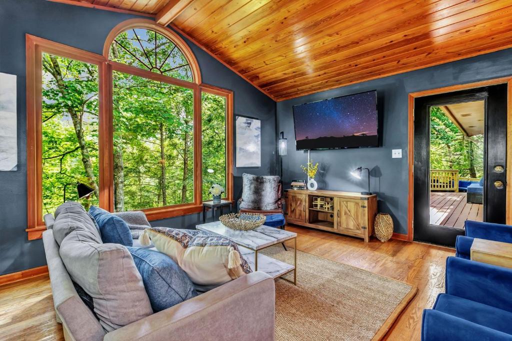 ein Wohnzimmer mit Sofa und Fernseher in der Unterkunft Cozy Serenity - Outdoor Hot Tub, Firepit, Games, + Close to Downtown Gatlinburg in Glade