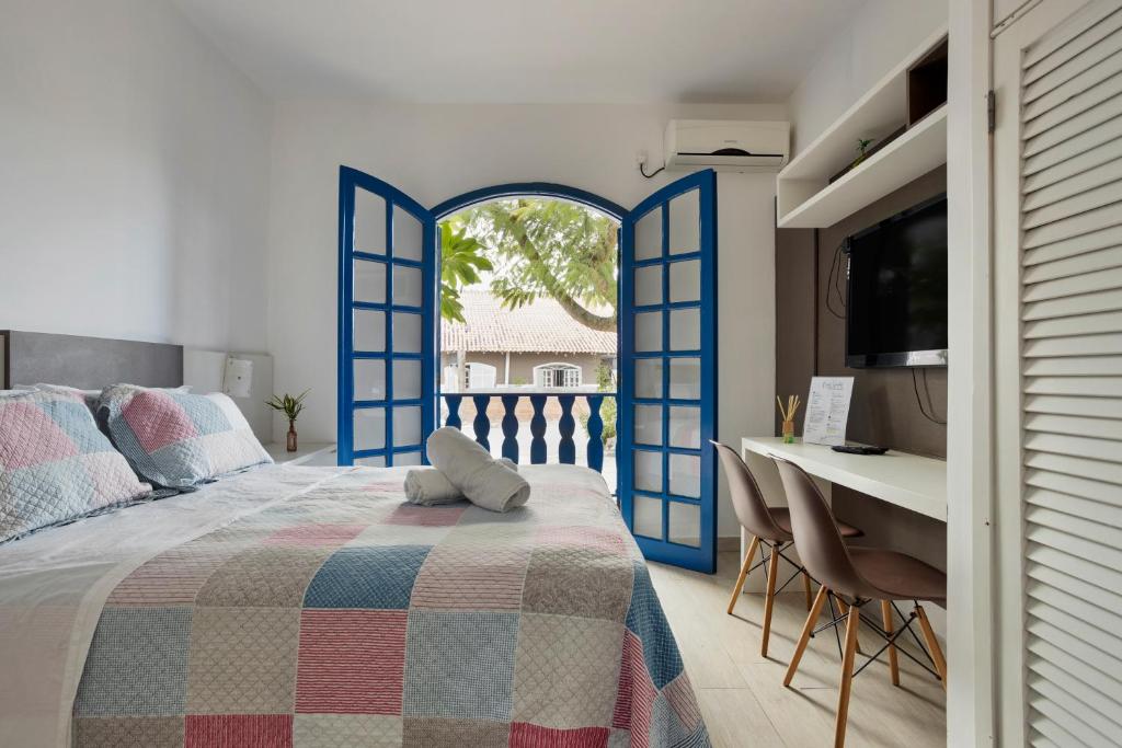 Un dormitorio con puertas azules y una cama y un escritorio. en Apartamentos 350m do mar, en Florianópolis