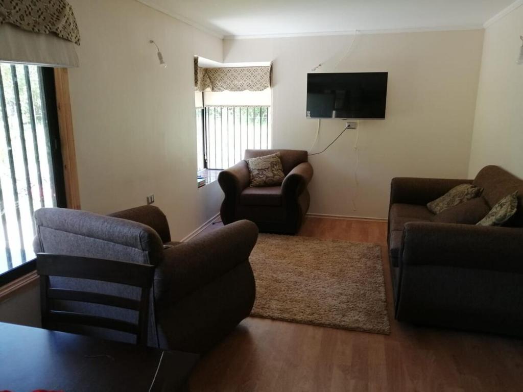 a living room with two couches and a flat screen tv at Pucón, casa en parcela in Pucón