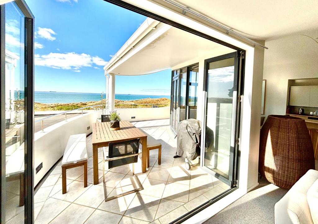 a balcony with a table and a view of the ocean at Supreme on Marine - Beachfront! in Mount Maunganui