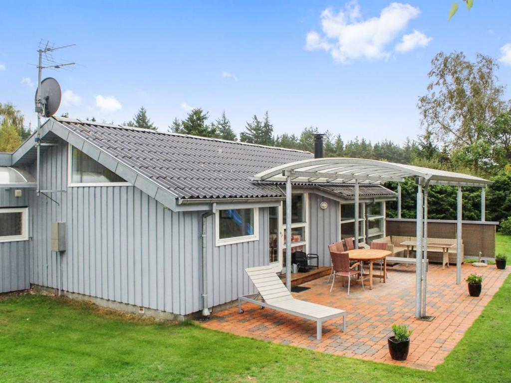 a house with a patio with a table and chairs at Holiday Home Albertina - 200m from the sea by Interhome in Hals