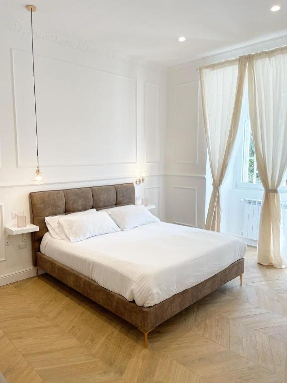 a large bed in a white bedroom with a large window at Fronte Reggia Apartment in Caserta