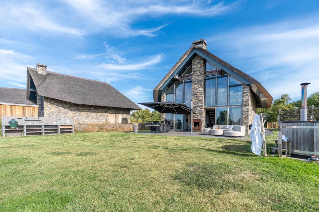 Elle offre une vue sur l'extérieur d'une maison en pierre dotée de grandes fenêtres. dans l'établissement Buytenplaats Villa 187, à De Koog