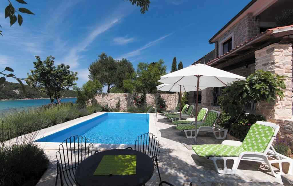 a swimming pool with chairs and an umbrella next to a house at Villa Pucalo by Villas Guide in Kampor