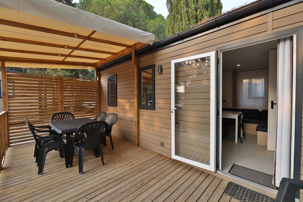 een terras met een tafel en stoelen op een dek bij Vertacoflav in Carry-le-Rouet