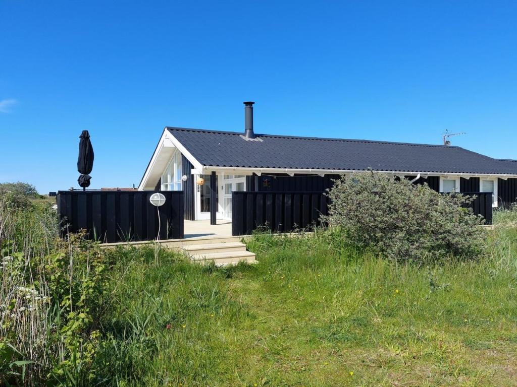 una casa blanca con techo negro en Holiday Home Sixten - 450m from the sea by Interhome, en Hjørring