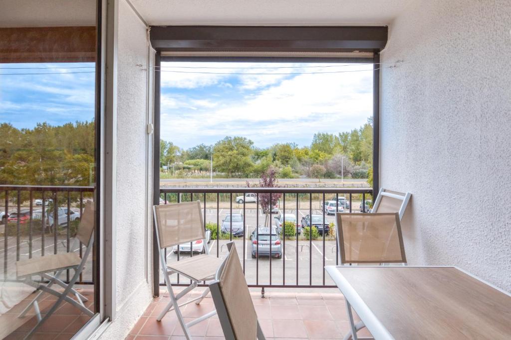 einen Balkon mit einem Tisch und Stühlen sowie Blick auf einen Parkplatz in der Unterkunft Le Grau-du-roi in Le Grau-du-Roi