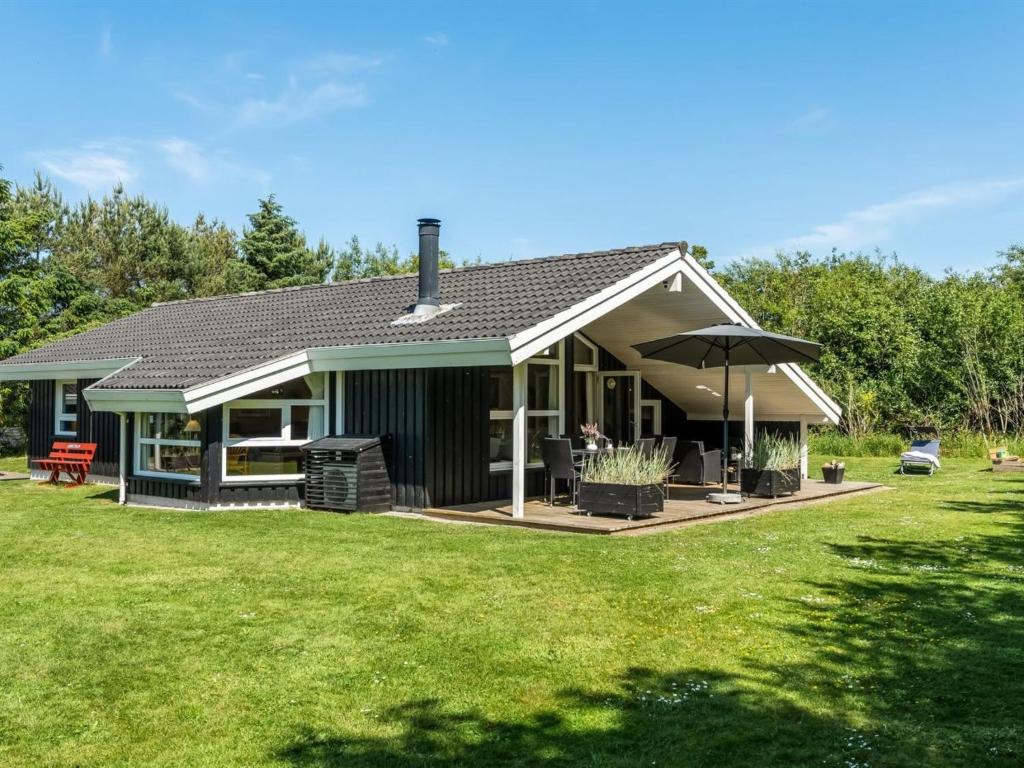 ein Haus mit einem Regenschirm auf einem Rasen in der Unterkunft Holiday Home Vilmar - 1-2km from the sea by Interhome in Hjørring