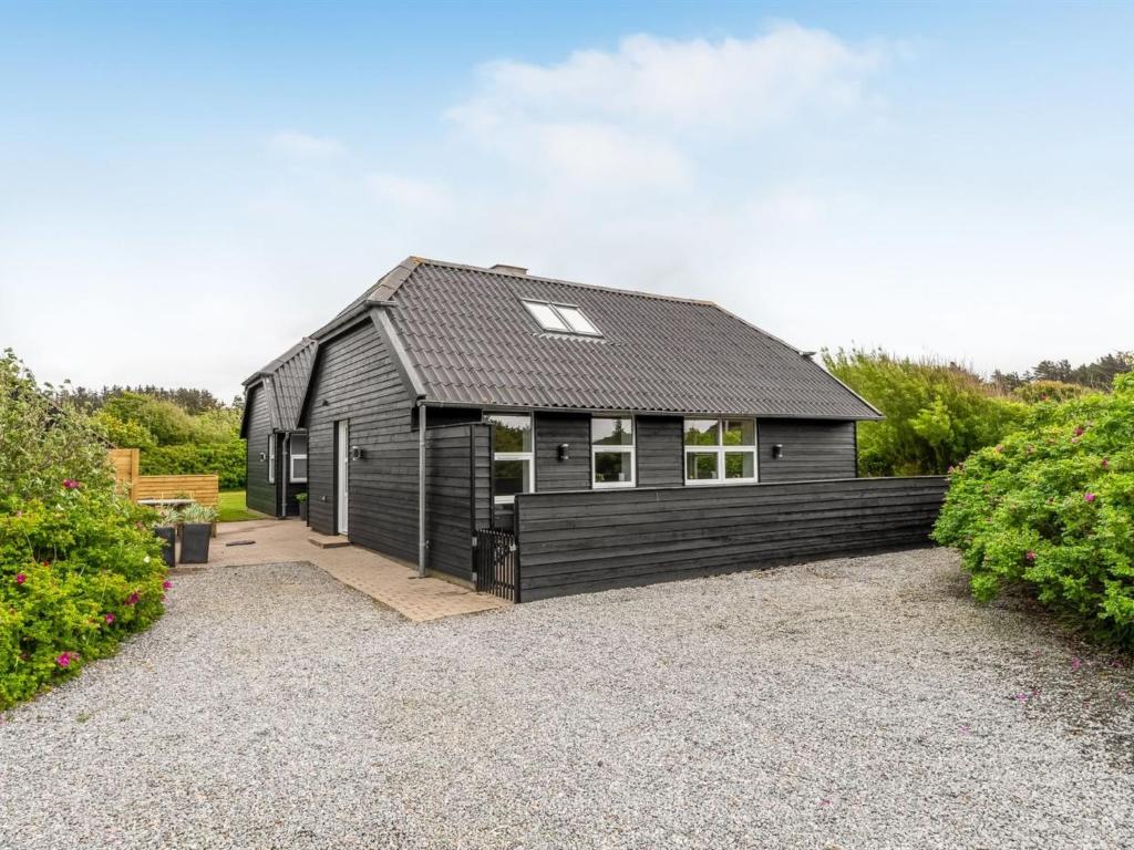 una casa negra con techo negro en Holiday Home Alfuin - 500m from the sea by Interhome, en Hjørring