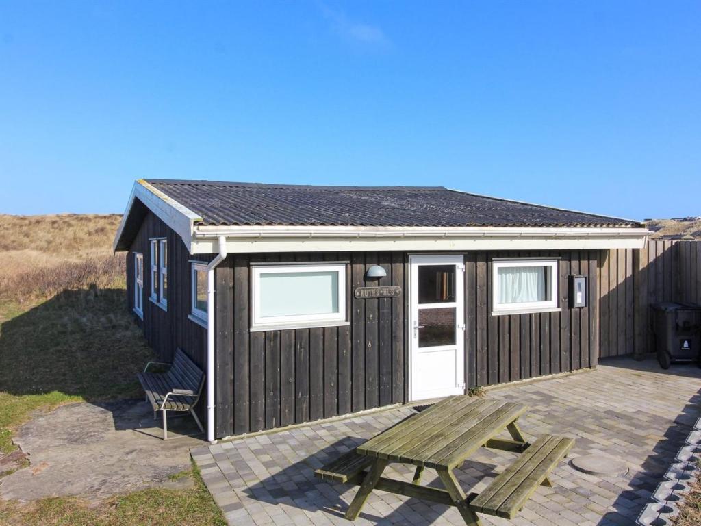 a tiny house with a picnic table and a bench at Holiday Home Nea - 234m from the sea by Interhome in Hirtshals