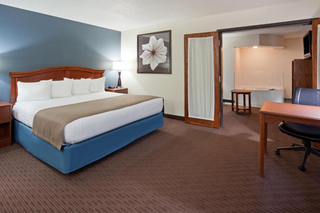 a hotel room with a bed and a desk at AmericInn by Wyndham Spencer in Spencer