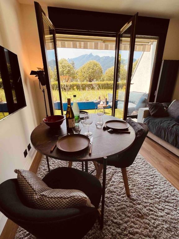 a table and chairs in a living room with a view at Studio bord du lac terrasse in Aix-les-Bains