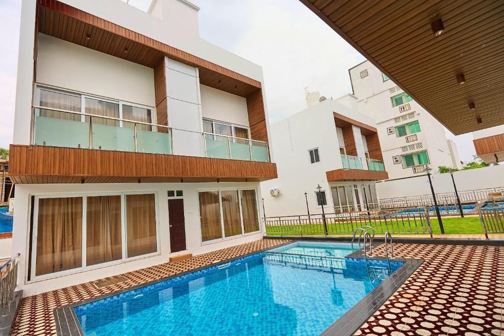 a swimming pool in front of a building at ASJ Holiday Villa in Puducherry