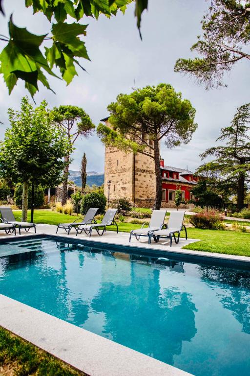 a swimming pool with chairs and a building in the background at El Torreón de Cepones in Segovia