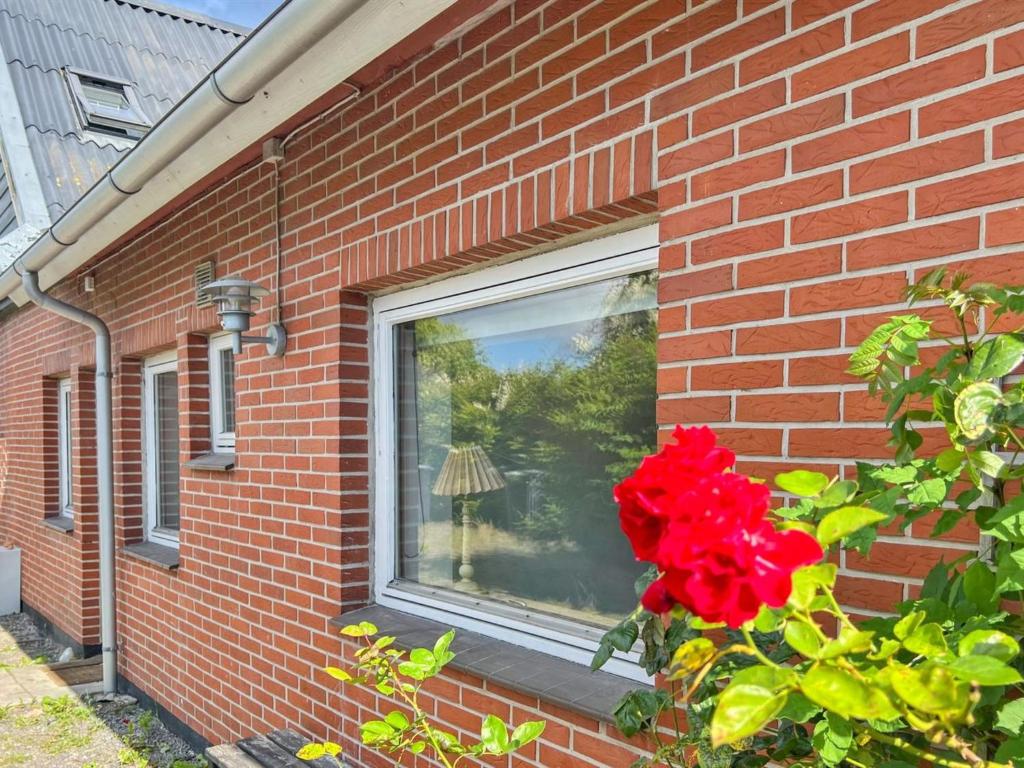 Una ventana de una casa de ladrillo con una rosa roja. en Apartment Atena - 250m from the sea by Interhome, en Neksø