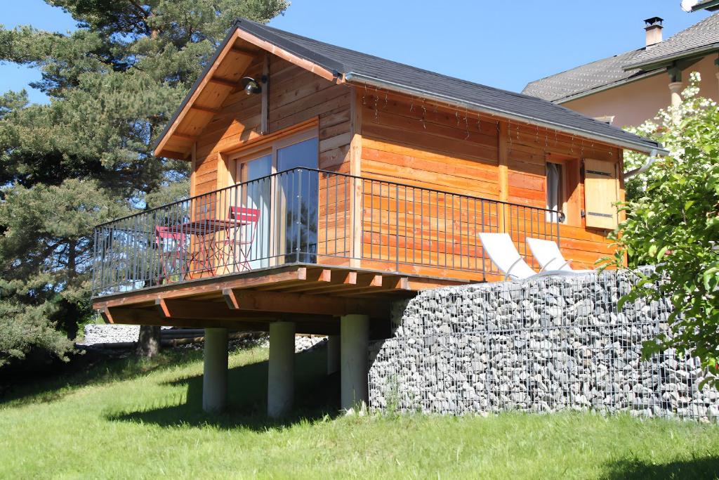 a log cabin with a deck and a stone wall at Shangri La in Saint-Jean-Saint-Nicolas