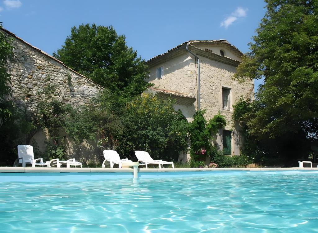 a swimming pool with chairs and a building at Appartement 2 in Montboucher-sur-Jabron