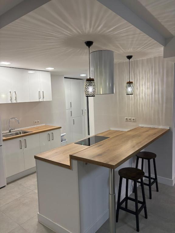 a kitchen with white cabinets and a wooden counter top at Apartamento en el centro de Móstoles in Madrid