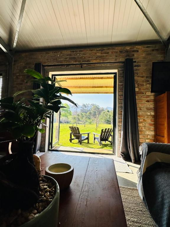 a living room with a table and a large window at Apple Cottage in Grabouw