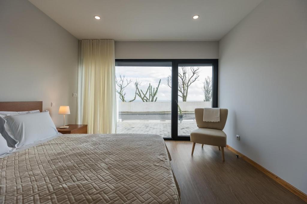 a bedroom with a bed and a chair and a window at Fonte Da Rocha - PIAS in Relva
