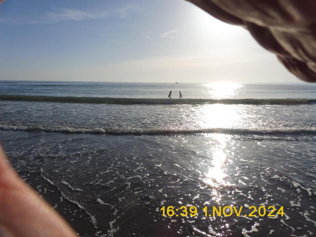 ein Strand mit zwei Menschen, die im Wasser laufen in der Unterkunft Les Alizes in Le Grau-dʼAgde