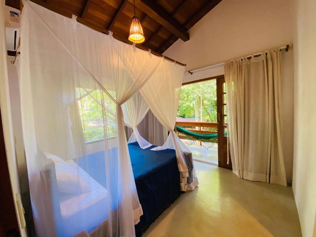 a bedroom with a bed with a mosquito net at Casa Gungalilin Trancoso in Trancoso