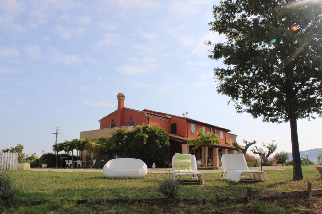 a house with two chairs and a tree in the grass at Colle del Giglio Resort & Spa in Ripatransone