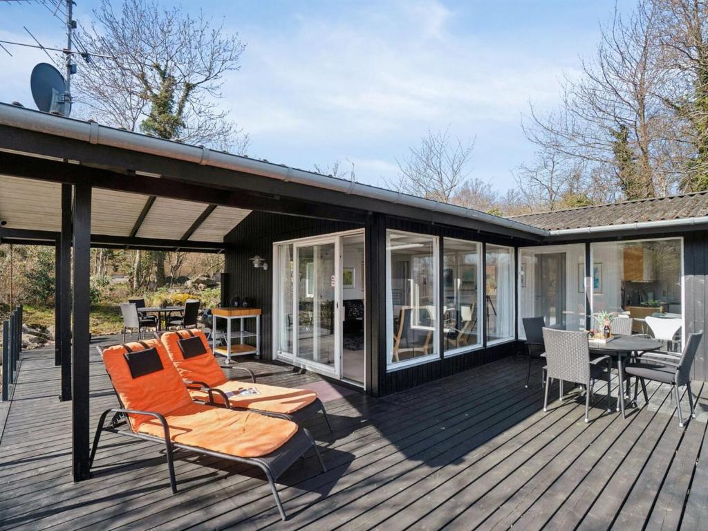 a deck with orange chairs and a table and chairs at Holiday Home Caren - 75m from the sea by Interhome in Allinge