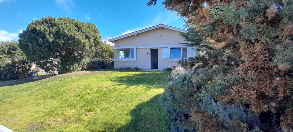 a small white house on a grassy field at Casa Bonita - Balneario RETA - alquiler temporario in Reta