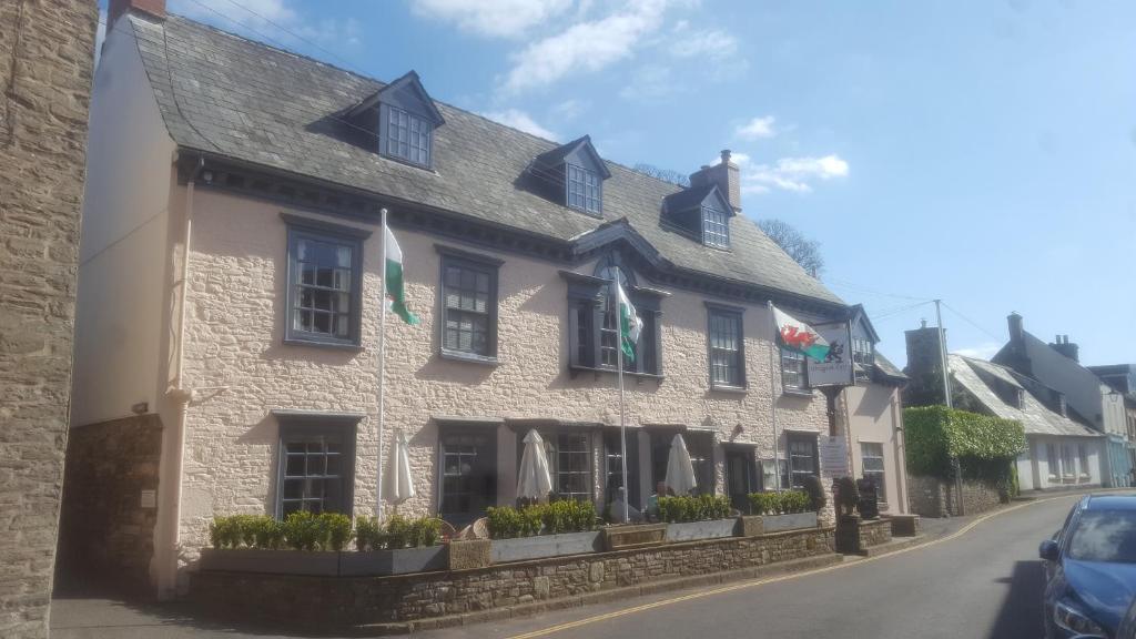 ein weißes Gebäude mit Flaggen auf einer Straße in der Unterkunft Dragon Inn in Crickhowell