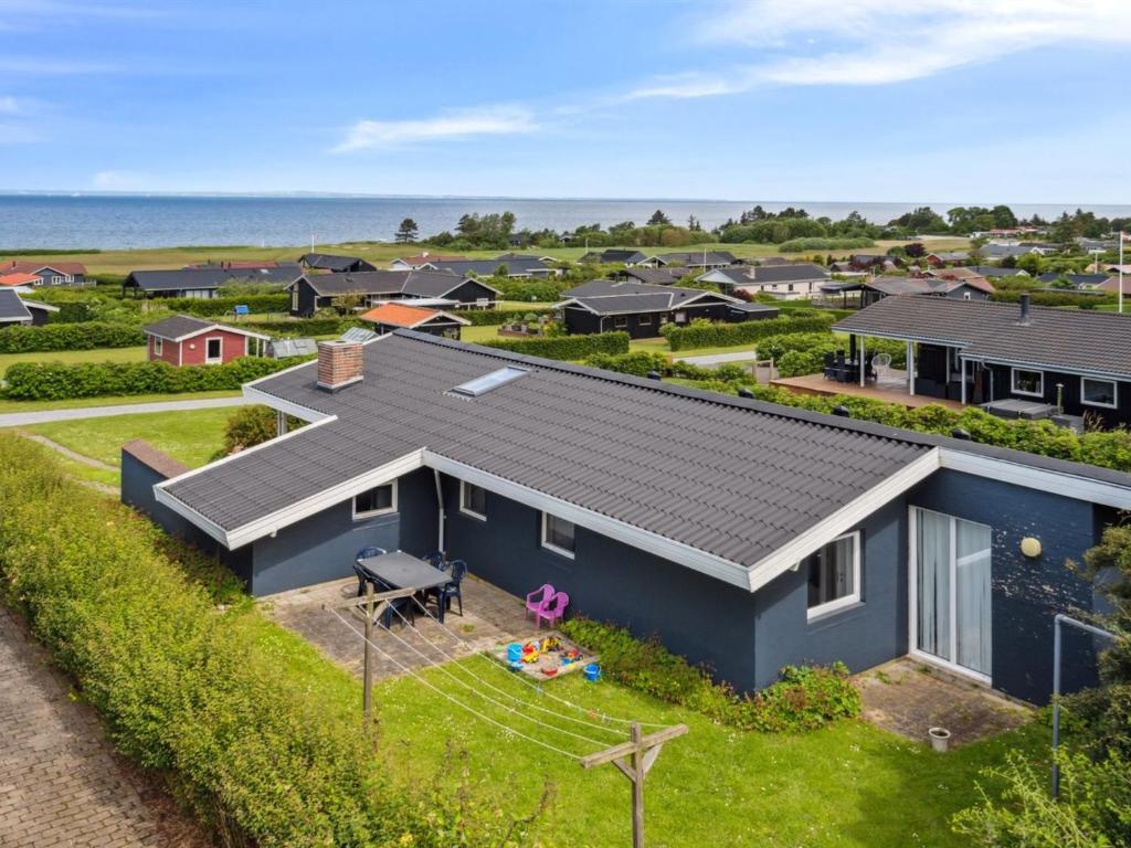 Vue aérienne d'une maison bleue avec l'océan en arrière-plan dans l'établissement Holiday Home Nelina - 300m from the sea by Interhome, à Bogense