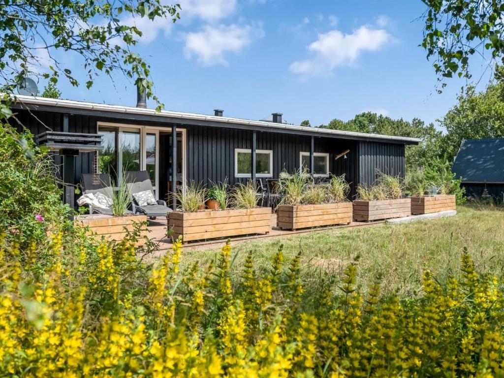 a black house with wooden planters and plants at Holiday Home Fatima - 1km from the sea by Interhome in Fanø