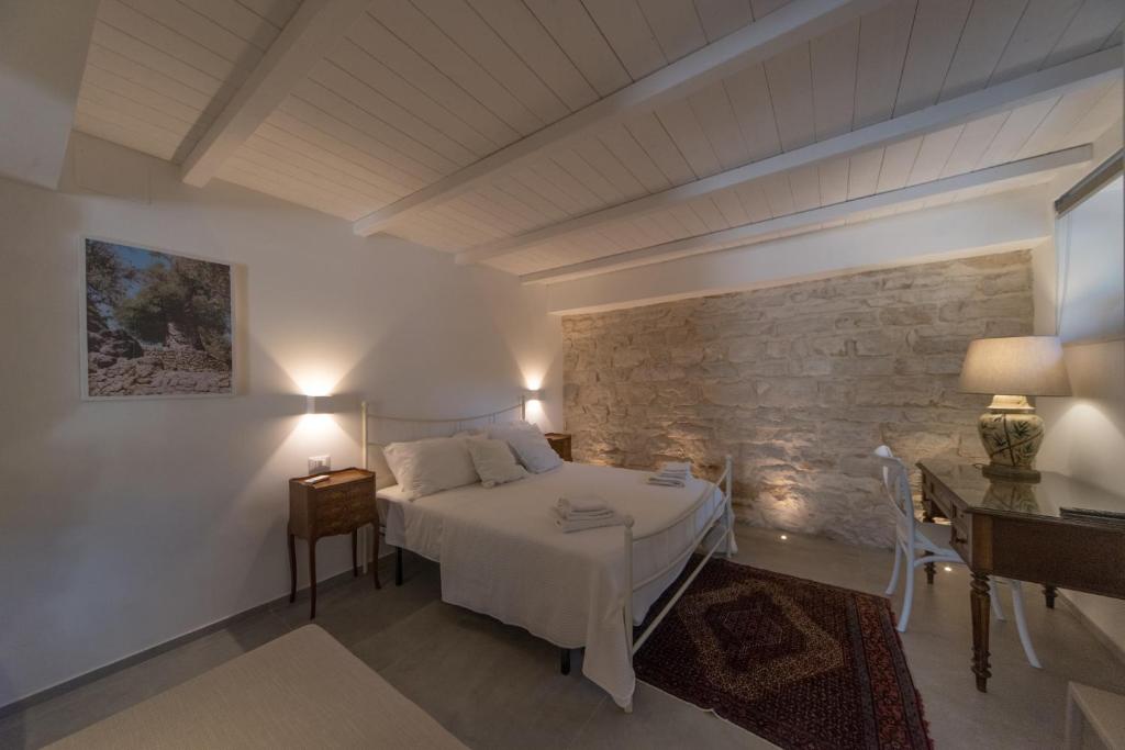 Un dormitorio con una cama blanca y una pared de piedra. en VILLA DEI PINI - Trani, en Trani