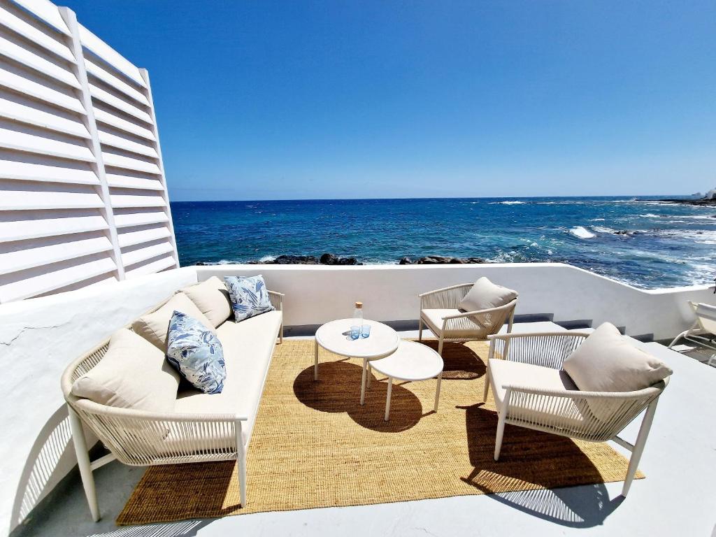 einen Balkon mit einem Sofa, Stühlen und Meerblick in der Unterkunft Casa Caracoles en Costa Teguise in Costa Teguise