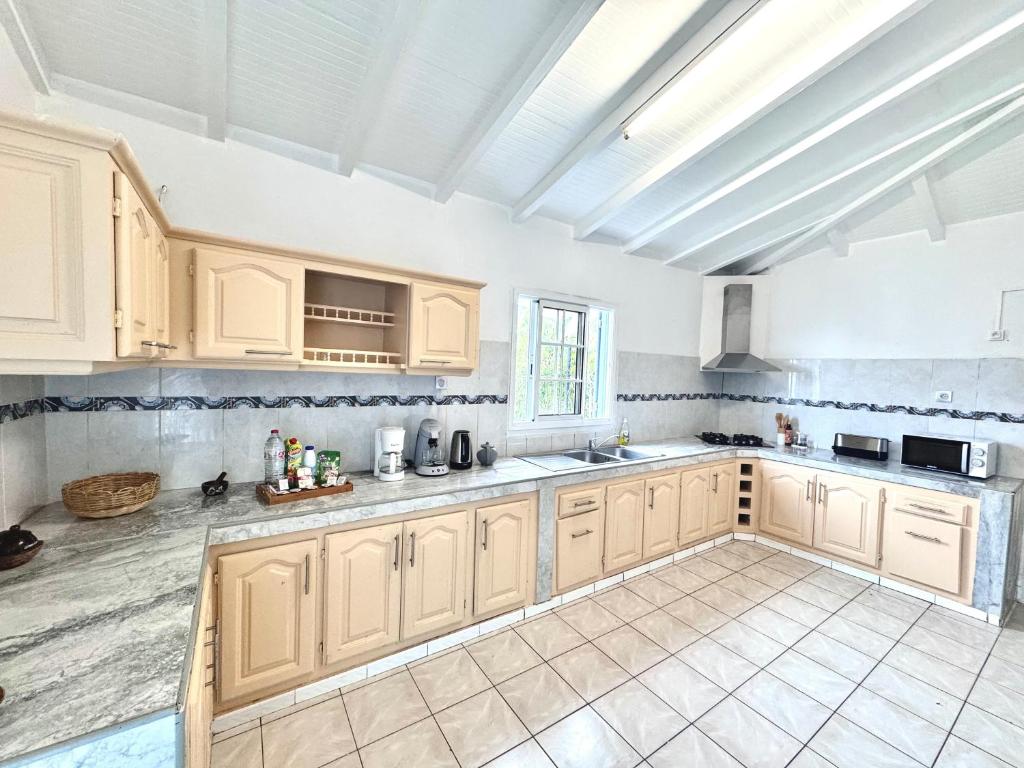 a large kitchen with white cabinets and a tile floor at Ameli'ber in Sainte-Rose