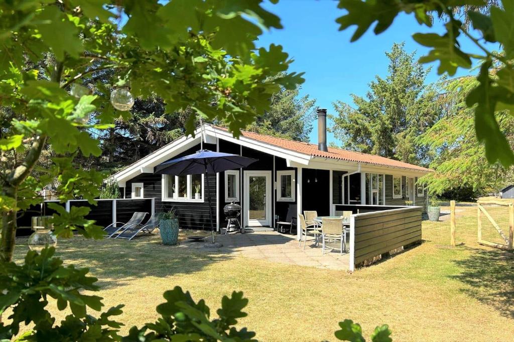 una casa con ombrellone e sedie in cortile di 40893-Ulfborg-Skindbjergvej-393 a Fjand Gårde