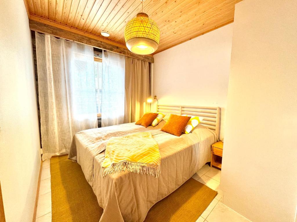 a bedroom with a bed with a yellow blanket on it at ÄkäsLuppo - Kelomökki, Sauna in Kittilä