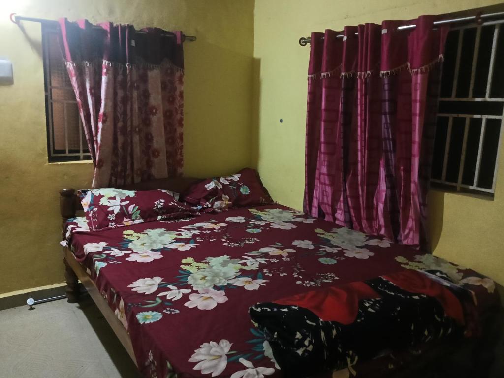 a bedroom with a bed with a floral bedspread at Nagamma guest house in Gokarna