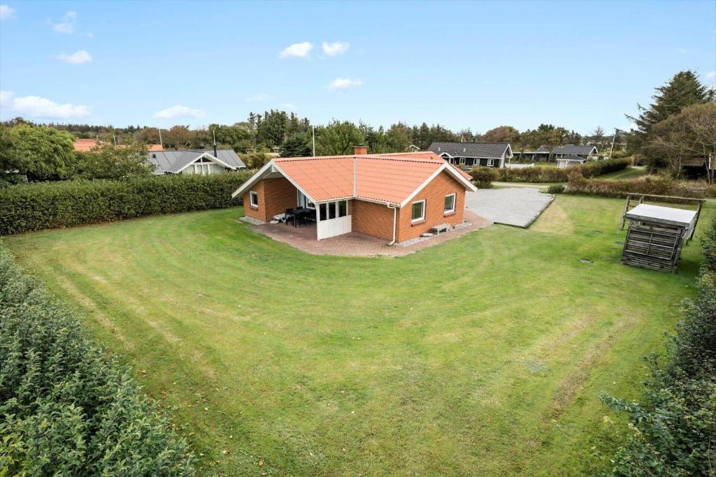 uma pequena casa em um quintal com um grande gramado em 40812-Ulfborg-Helmklit-214 em Fjand Gårde