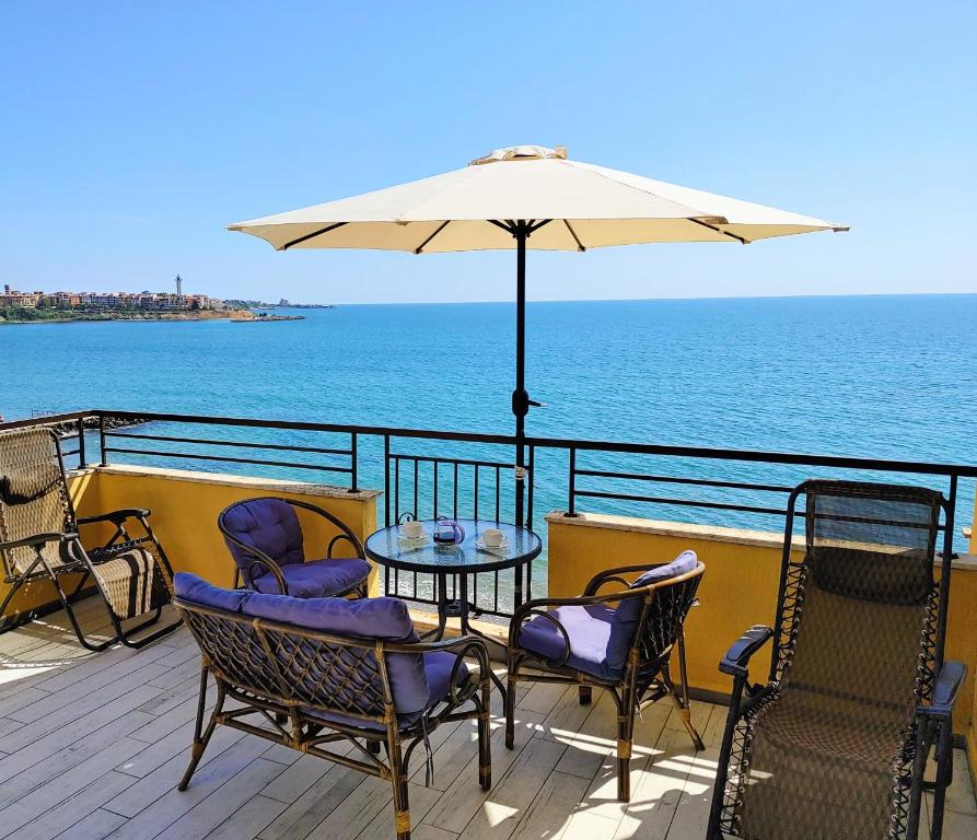 a patio with a table and chairs and an umbrella at AKB Apartment Sea View in Aheloy