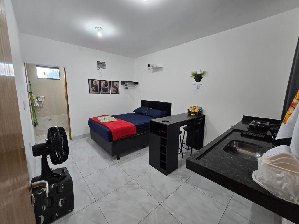 a room with a bed and a desk in it at Flat completo 12 minutos do centro com lojas variadas in Aparecida de Goiania