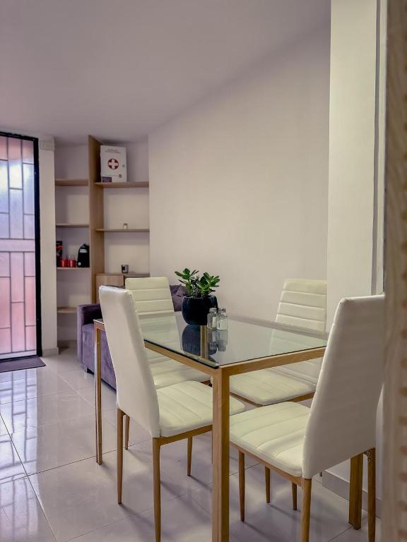 パルミラにあるApartamento primer piso CR Villa Roma Las Mercedesのガラスのテーブルと白い椅子のあるダイニングルーム