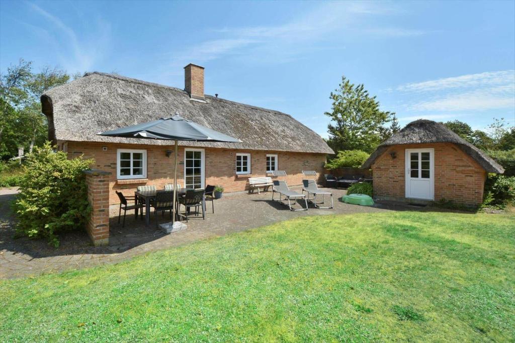 uma casa com uma mesa, cadeiras e um guarda-chuva em 30848-Ulfborg-Valmuevej-286 em Vang