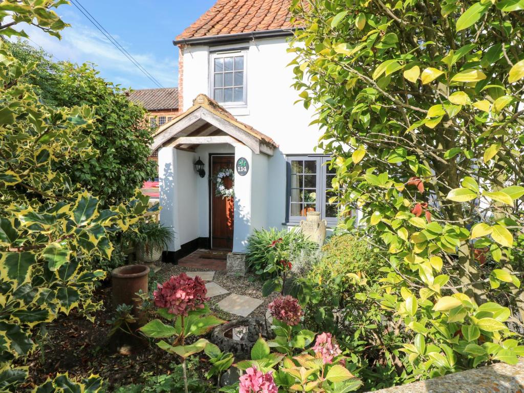 een wit huis met een tuin ervoor bij Hollyhedge Cottage in Briston