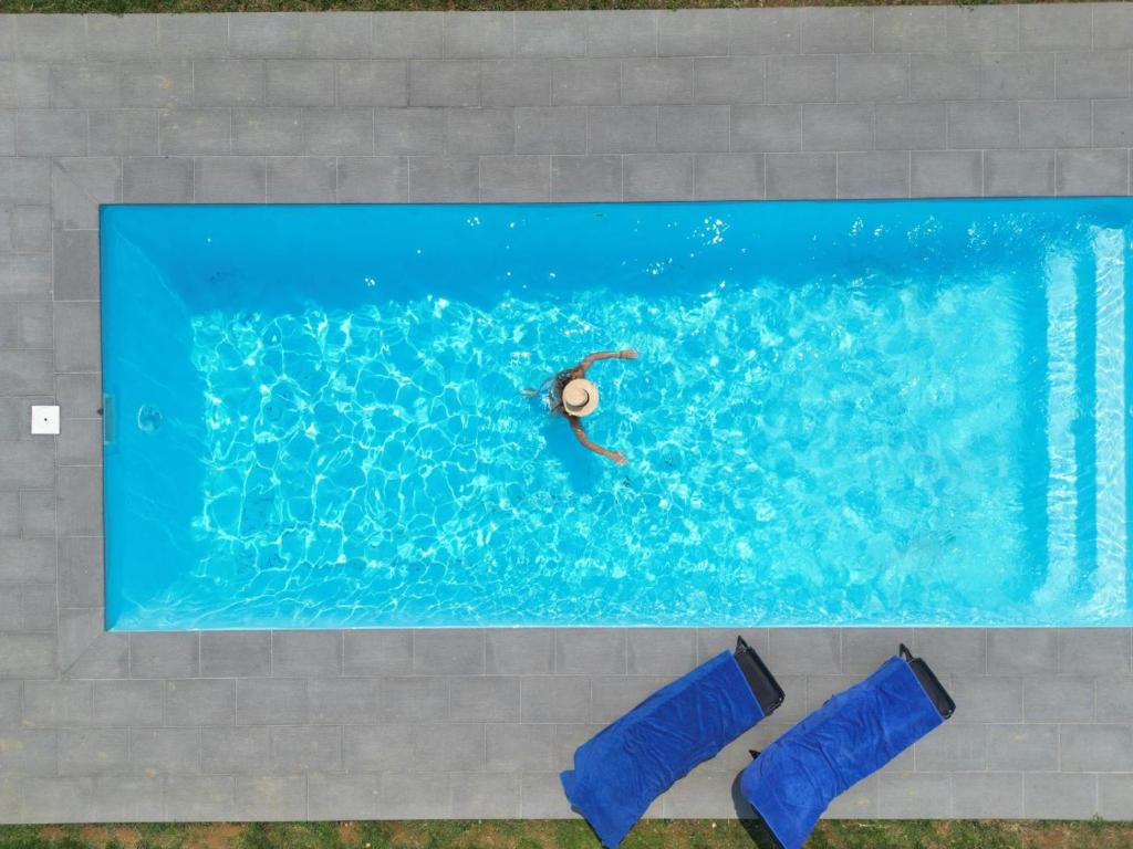a person swimming in a pool with two blue chairs at Casa De Vilar do Dão in Penalva do Castelo