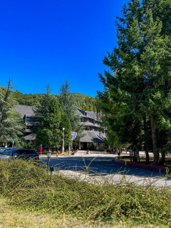 a street with a parking lot with a building and trees at Hotel Junior in Kopaonik